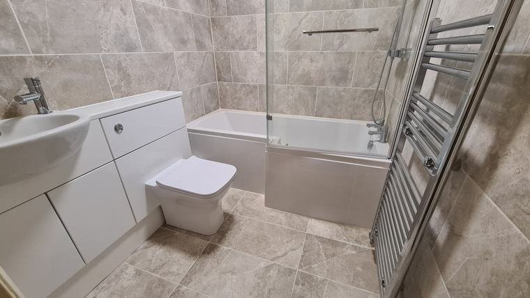 Grey tiled bathroom with shower bath