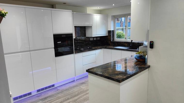 White kitchen with dark worktops and plinth lighting